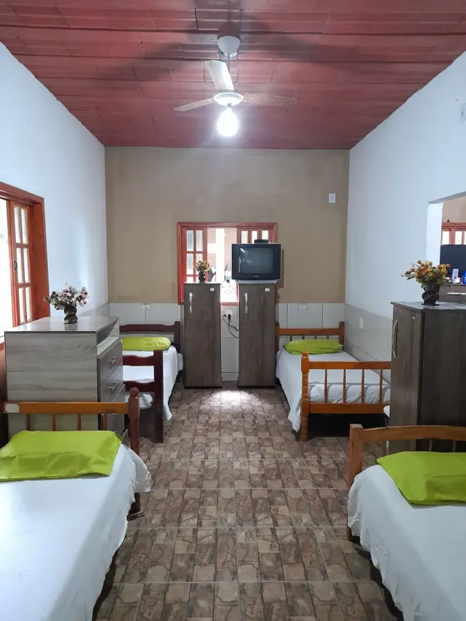Quarto coletivo amplo e arejado, com televisão e armários individuais para os residentes